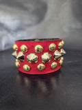 Red punk wrist cuff with silver and gold colored spikes.