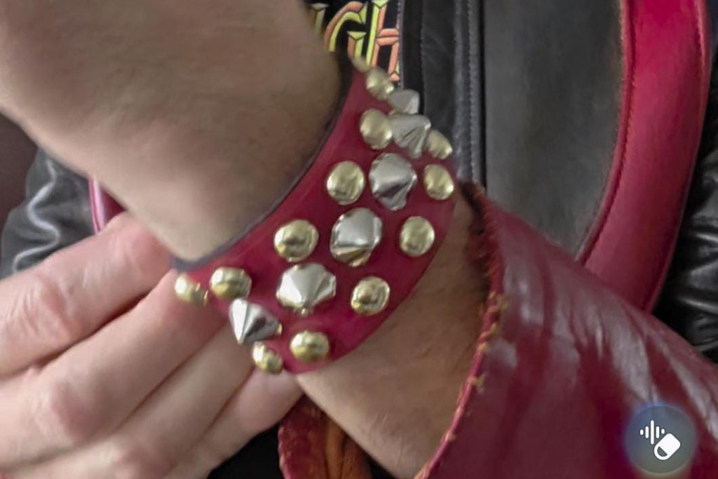 Red punk wrist cuff with silver and gold colored spikes.