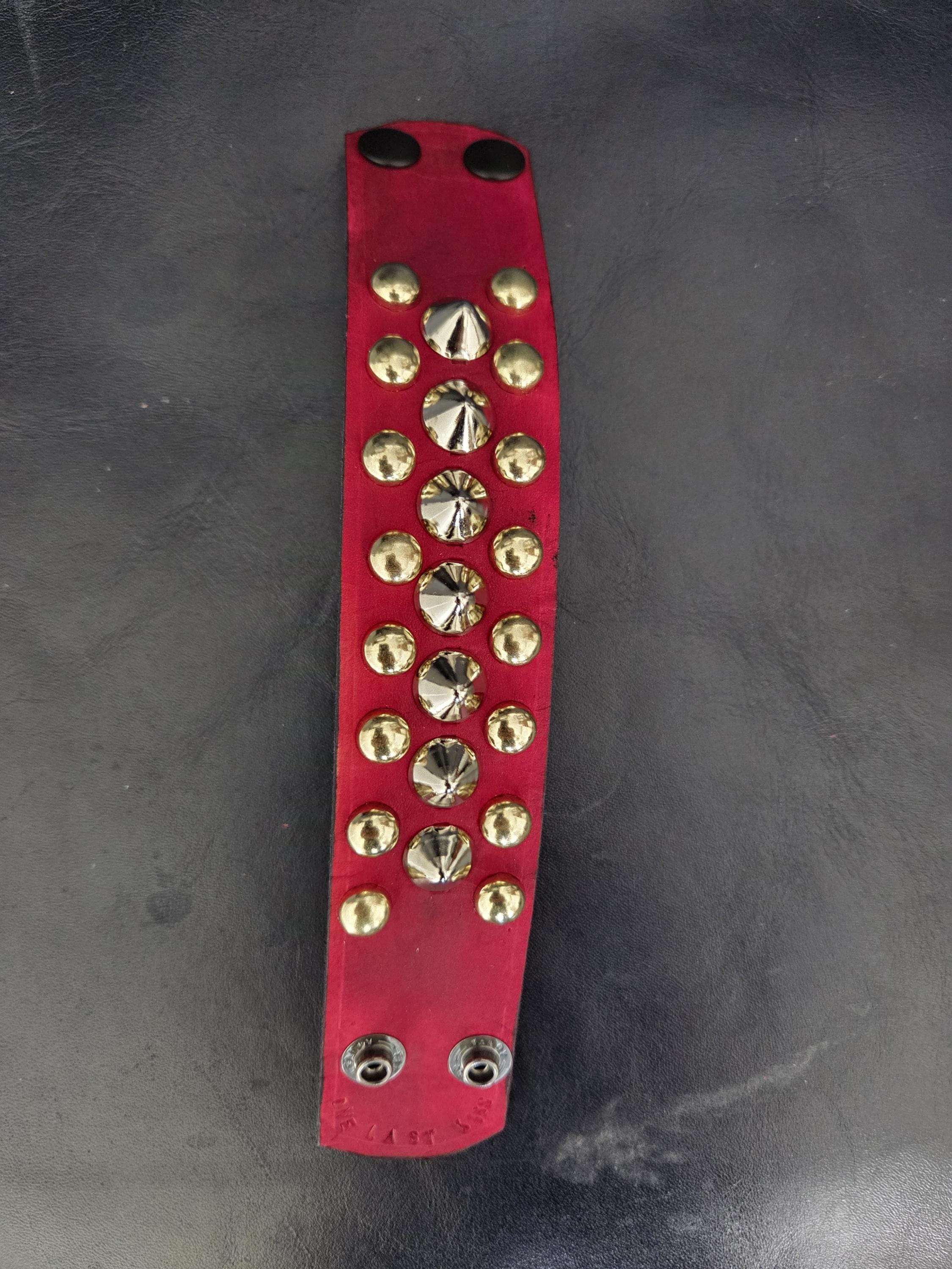 Red punk wrist cuff with silver and gold colored spikes.