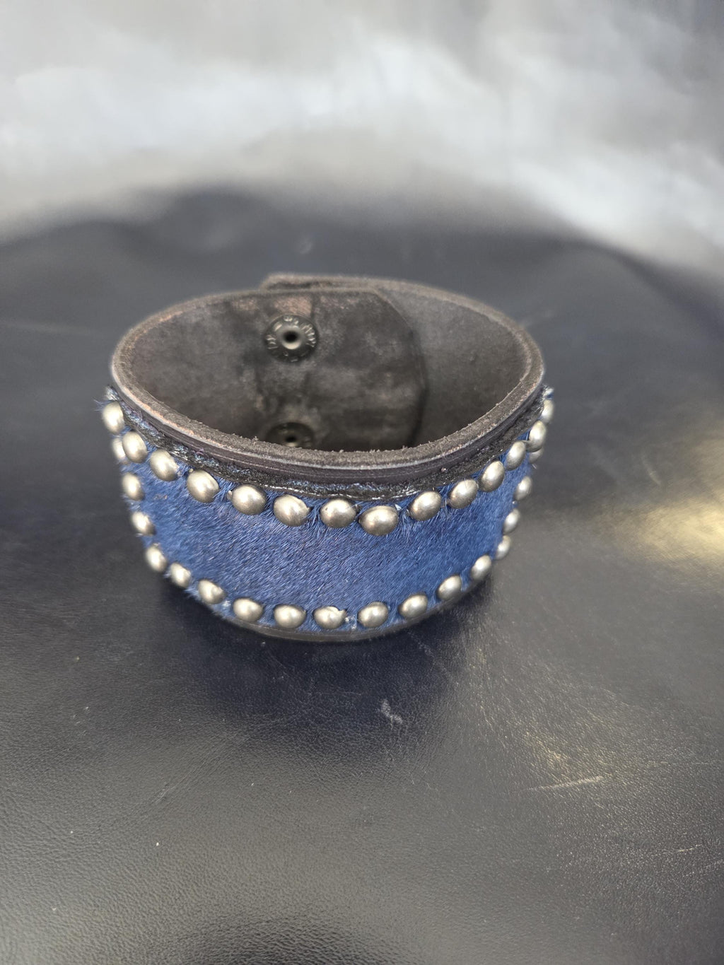Studded wristband with navy blue hair-on-hide leather.