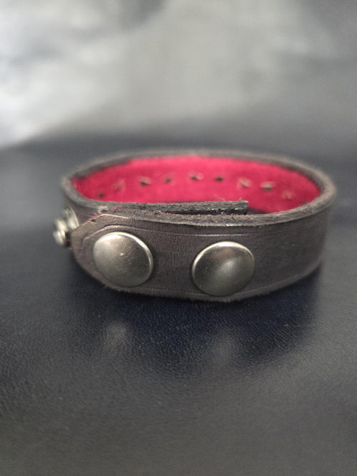Leather bracelet with red jewel studs.
