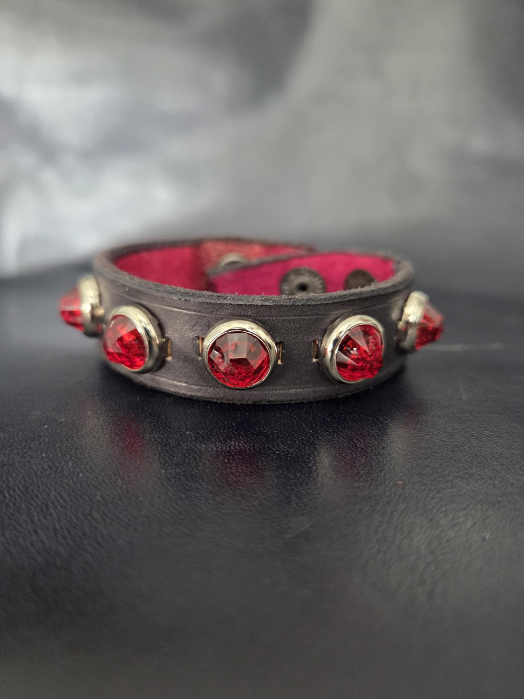 Leather bracelet with red jewel studs.