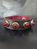 Leather bracelet with red jewel studs.
